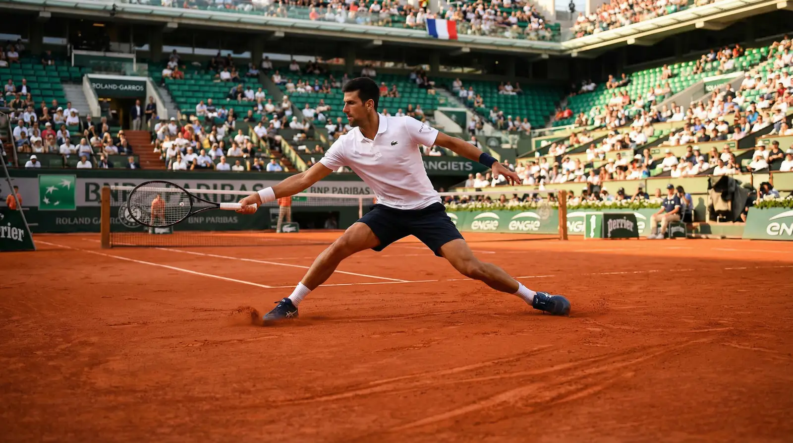 Tennisspieler rutscht auf rotem Sandplatz in Paris bei Grundlinienschlag
